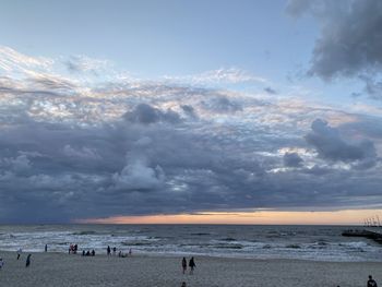 People on beach against sky during sunset