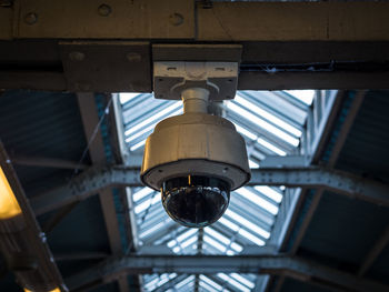 Low angle view of security camera hanging on ceiling in train station