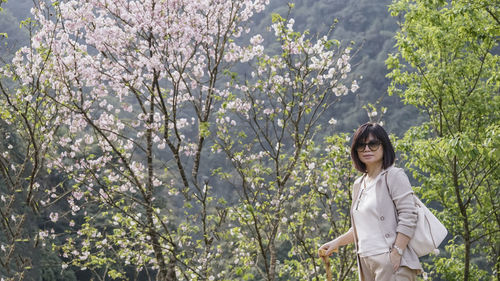 Full length of woman standing by flower tree