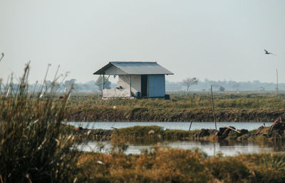 House by lake against clear sky