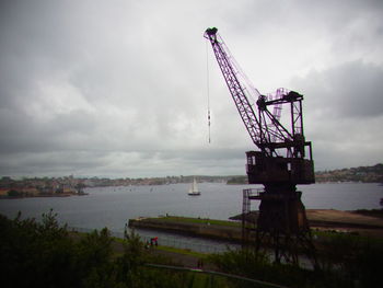 Crane by sea against sky