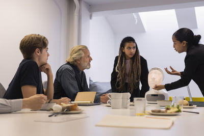 Business people discussing robot voice assistant during meeting