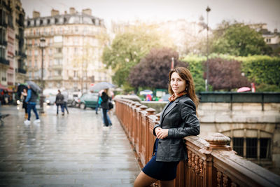 Brunette girl in a black jacket stands on the bridge