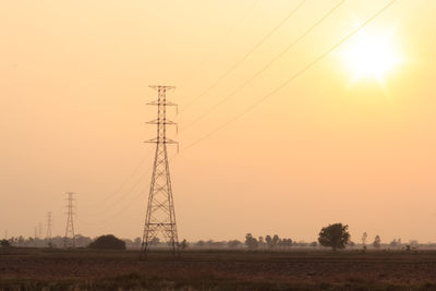 Electricity pylon on field against sky during sunset