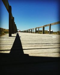 View of wooden walkway against clear sky