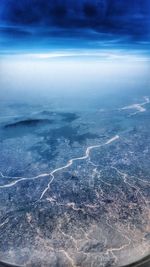 Aerial view of landscape by sea against blue sky