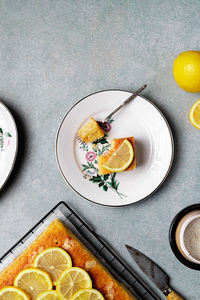 Top view of square slice of delicious homemade lemon cake served on plate with fork on tray