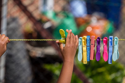 Close-up of hand holding clothespins hanging on clothesline