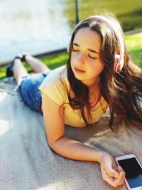 Girl with eyes closed listening music in park