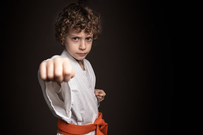 Portrait of boy standing against black background