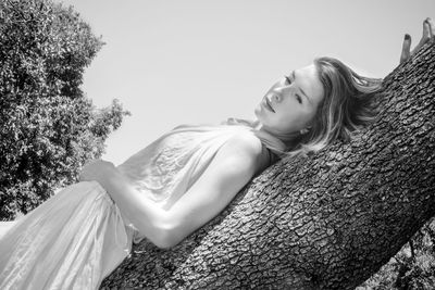 Low angle view of young woman against clear sky