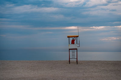 Lifeguard in hut against cloudy sky and sea