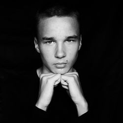 Close-up portrait of young man against black background