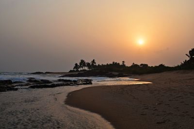 Scenic view of beach against clear sky during sunset