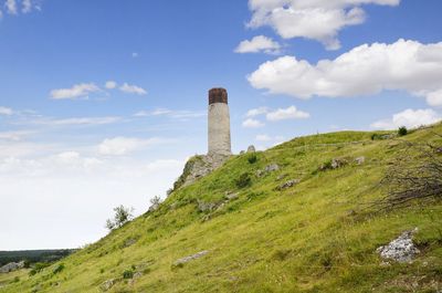 Lighthouse on field against sky