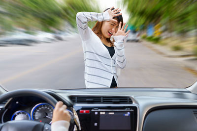 Scared woman in front of car seen through windshield