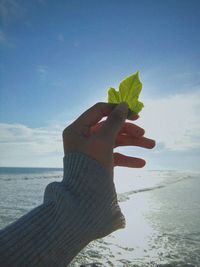 Close-up of woman hand holding sand against sea