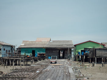 Old houses by building against clear sky