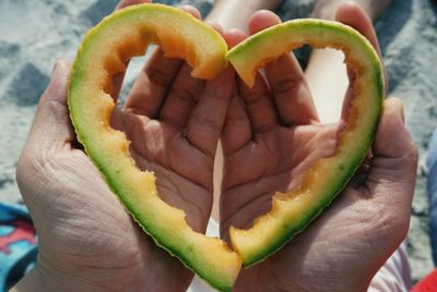 Close-up of person with heart shape muskmelon peel at beach