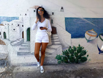 Portrait of young woman standing against wall