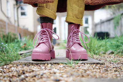 Woman with pink color shoe standing on footpath