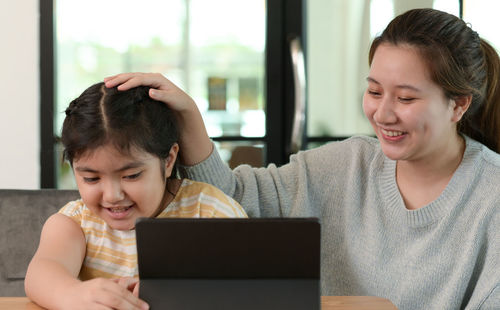 Asian girl studying privately with tutor at home, siblings teaching homework, online learning.