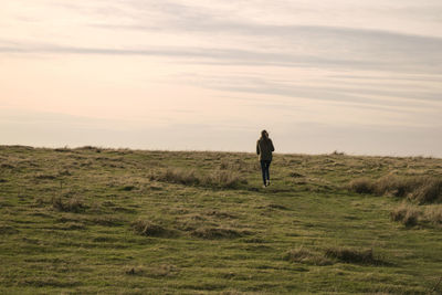 Full length of woman walking on field against sky