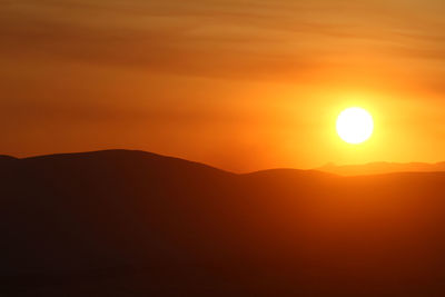 Scenic view of silhouette mountains against romantic sky at sunset
