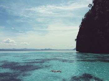 Young woman swimming in sea against sky during sunny day