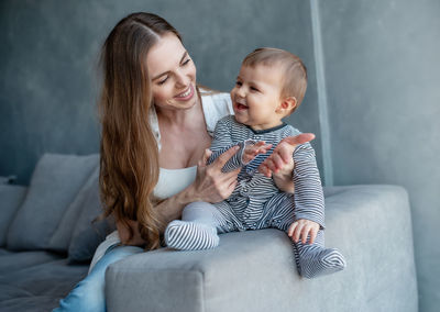 Mother and daughter sitting on sofa at home