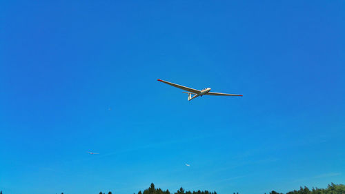 Low angle view of airplane flying against blue sky