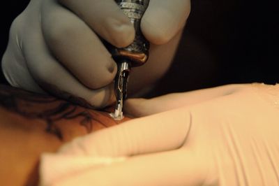 Cropped image of tattoo artist preparing tattoo on hand