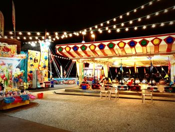 Illuminated carousel in amusement park at night