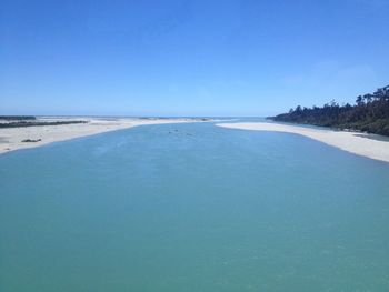 Scenic view of beach against clear blue sky