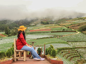 Rear view of woman sitting on field