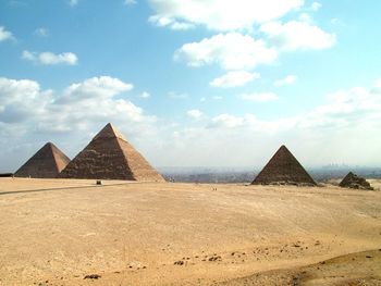 Pyramids at desert against sky during sunny day