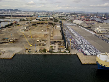 Aerial logistics commercial vehicles waiting to be load on to a car carrier ship at dockyard