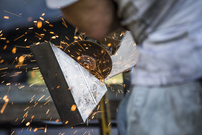 Close-up of worker using angle grinder in a factory