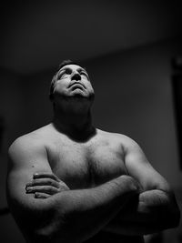 Shirtless man standing against wall