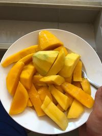 Close-up of hand holding fruit salad in bowl