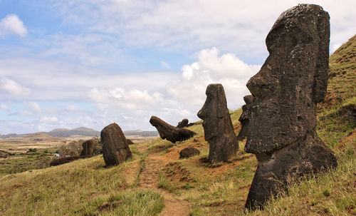 Scenic view of sculptures on landscape against cloudy sky