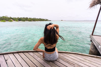 Rear view of young woman in swimming pool against sky