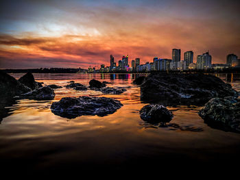 Panoramic view of sea and buildings against sky during sunset