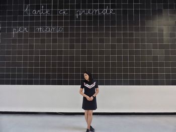 Full length of woman standing against wall