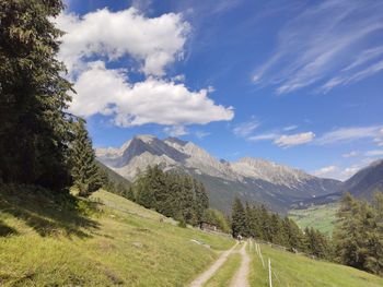 Country road by mountains against sky