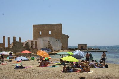 People at beach against clear sky