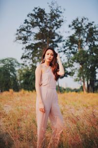 Portrait of smiling young woman standing on field