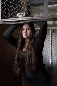 Portrait of young woman standing against window