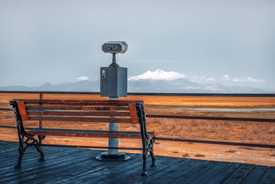 Empty bench against scenic view of mountains against sky