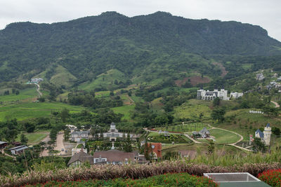 Houses on field by buildings against mountains